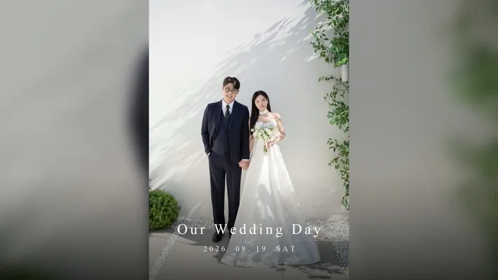 정장 차림 신랑과 드레스 입은 신부가 흰 벽 앞에 선 사진 위로 Our Wedding Day 자막이 뜨는 식전영상 첫 장면
